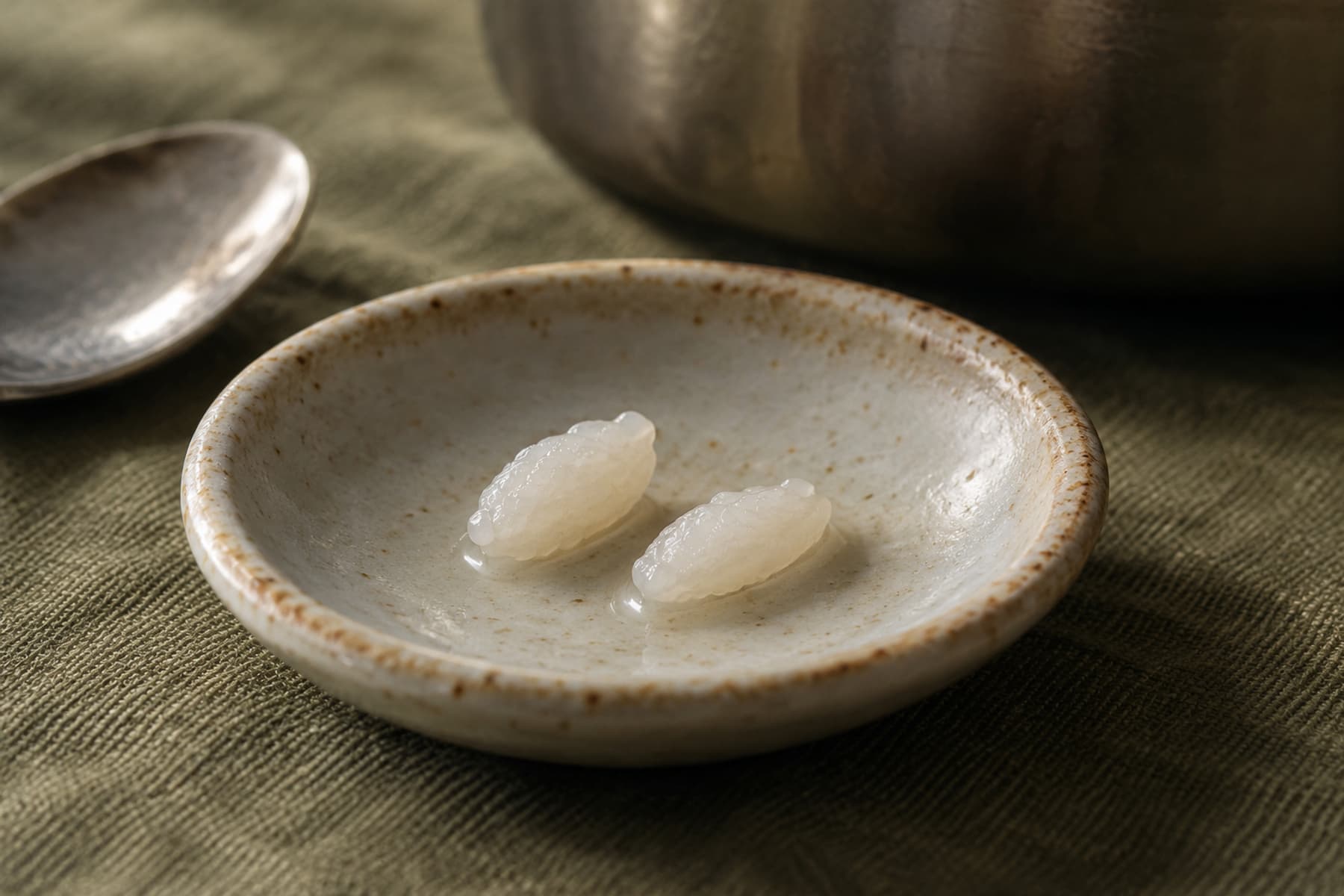 작은 받침에 덜어 놓은 익힌 쌀알 두 개.