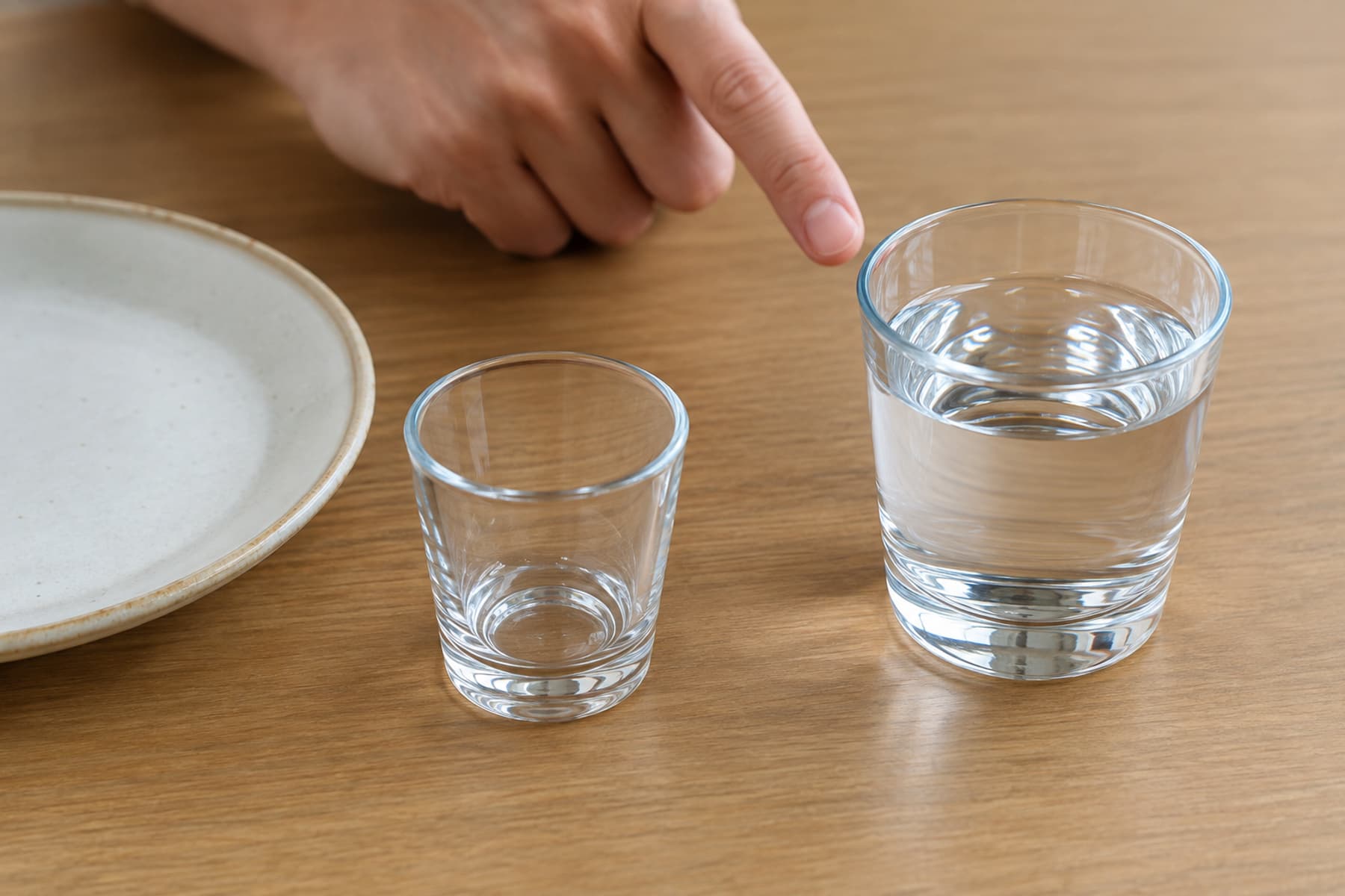물잔과 빈 작은 잔을 구별하는 식탁의 손